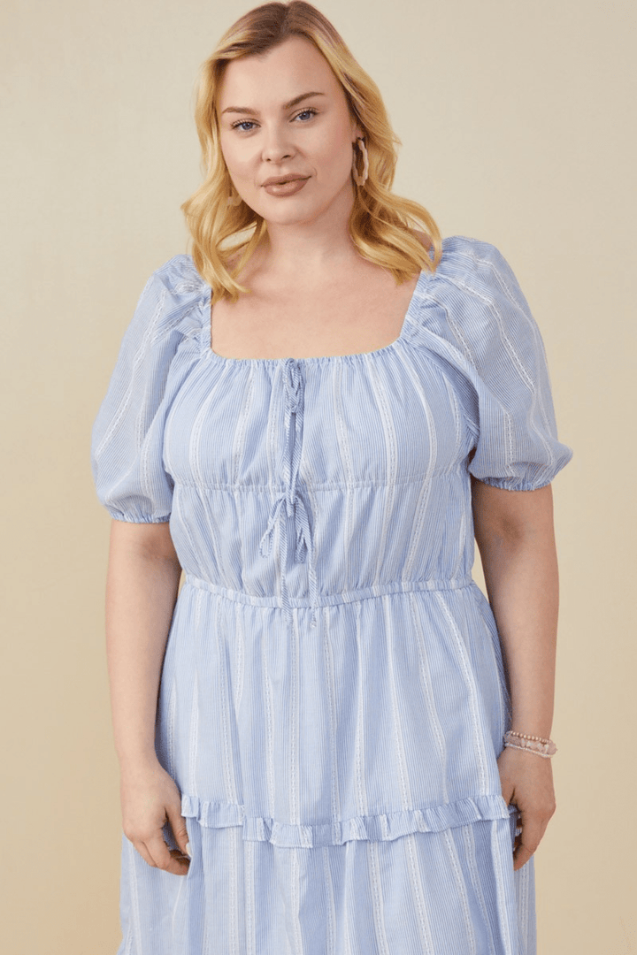 Plus-size model wearing the Iliana blue crochet lace midi dress with bow detail and square neckline – available at Ari + Ava