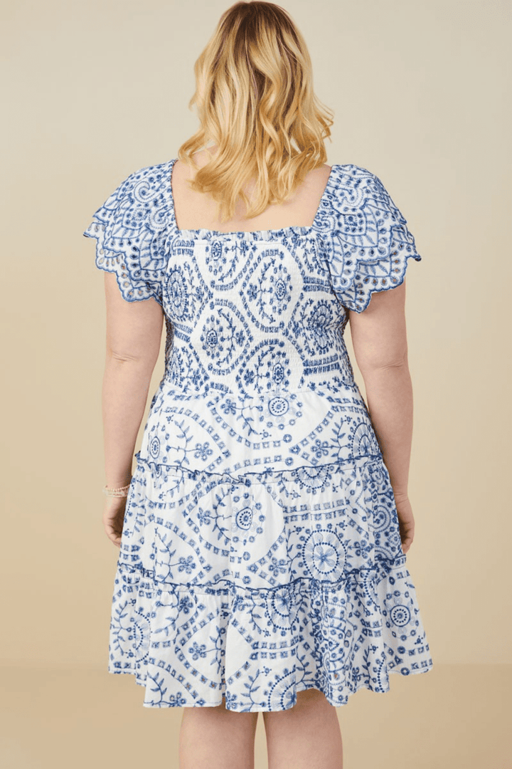 Plus-size model wearing the Jolie blue eyelet embroidered dress with scalloped hem and ruffled sleeves – available at Ari + Ava